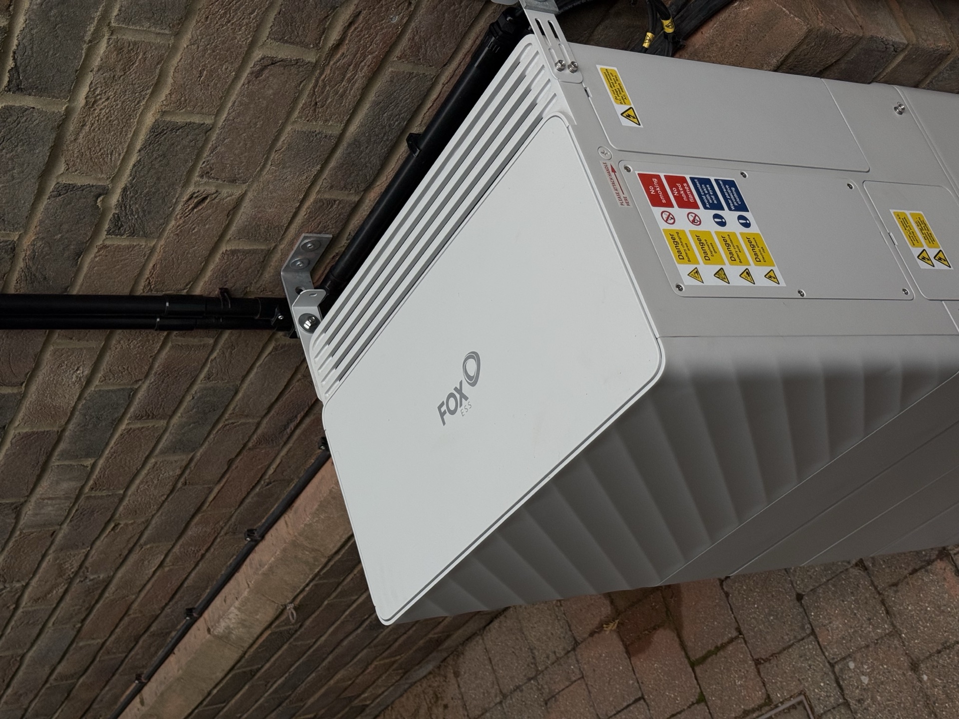 Fox ESS home battery wall-mounted on a brick exterior